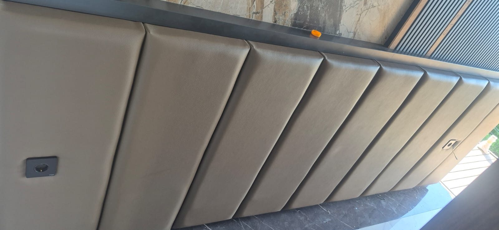 Sofa modern berwarna kulit cokelat hangat di ruang tamu dengan cahaya siang — referensi visual sofa dan upholstery.